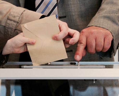 mans dipositant el vot en una urna