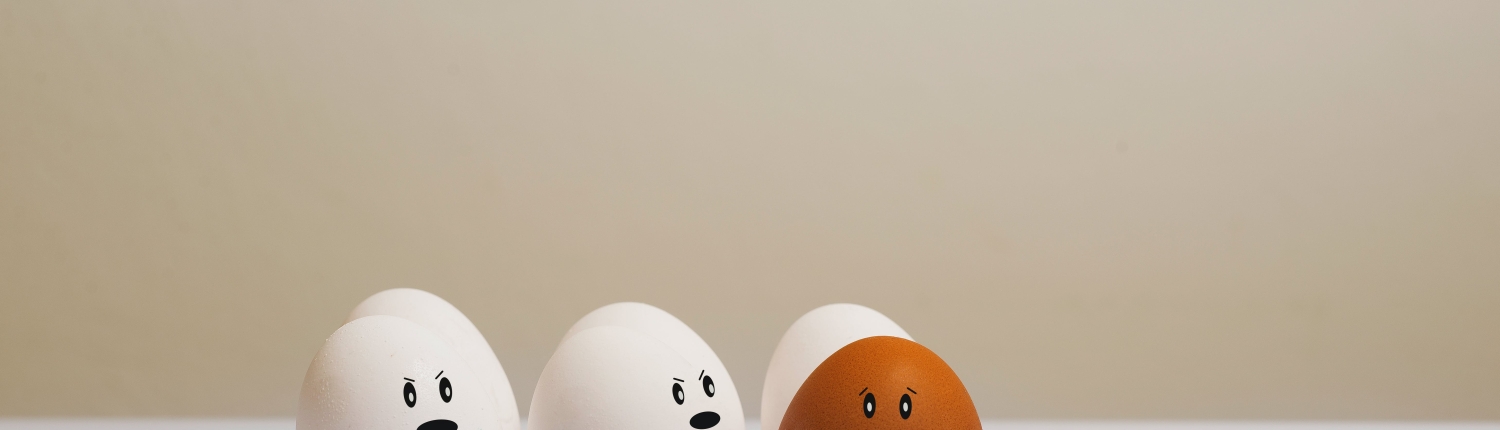 Una cesta de huevos blancos junto a uno moreno